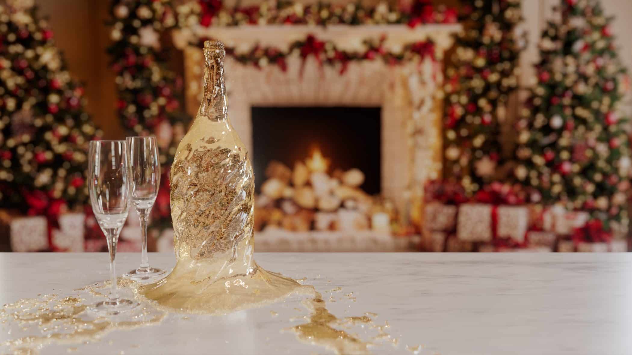 Champagne falling out of the shape of the bottle as the glass is no longer there. In front of a Christmas fire place and tree.