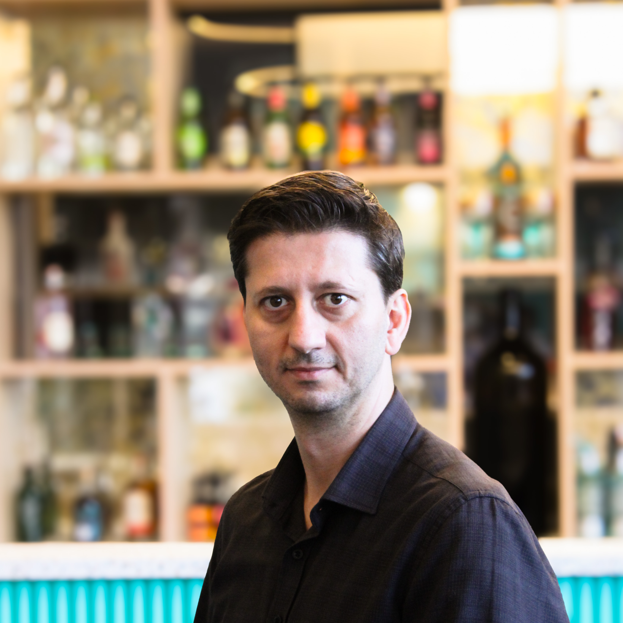 Hakan Bicak, a man with dark hair wearing a black shirt, sat in front of a bar.